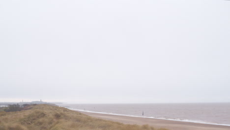 UK-English-Norfolk-Coast-beach-seaside-in-stormy-weather-with-fog-and-mist-over-sea-and-dunes-in-foreground