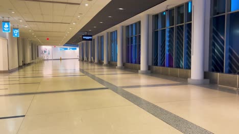 moving slowly through an empty airport terminal corridor with blue lights and pillars at night