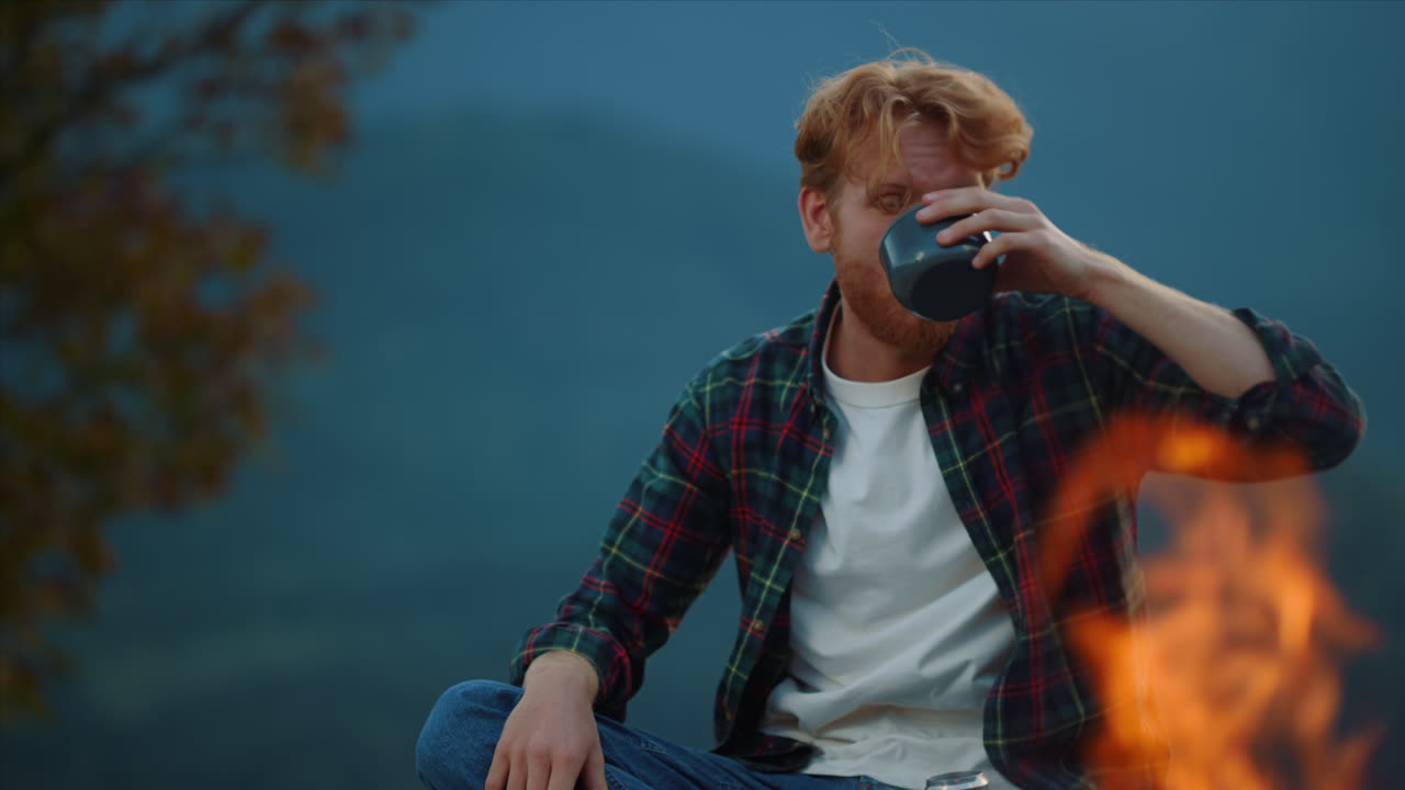 los campistas cansados se relajan beben té en las montañas, la naturaleza al atardecer, los hipsters disfrutan de la fogata.