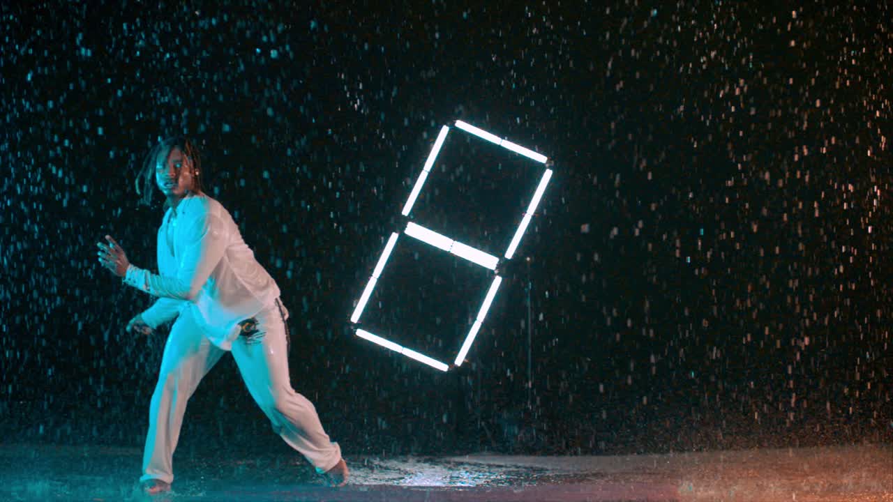 Capoeira dancer performing upside down tricks in the rain in super slow motion