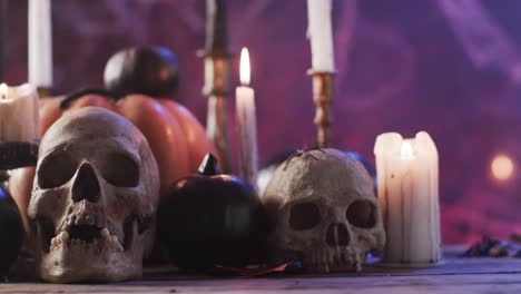 Video-of-halloween-skulls,-candles-and-smoke-with-copy-space-on-purple-background