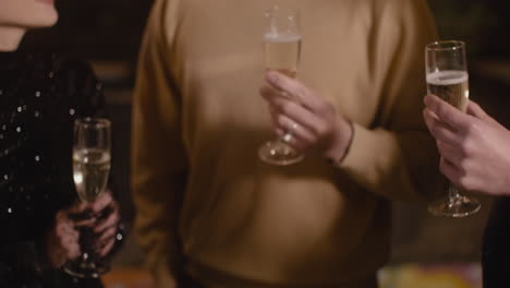 close up of unrecognizable friends toasting with champagne glasses at new year's eve party