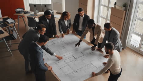 team of architects and engineers reviewing blueprints in an office meeting