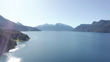 aerial - sunny reflection on traful lake, patagonia, río negro, argentina, truck right