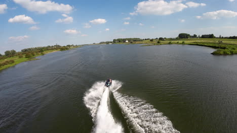 fpv aerial of a jetski riding on wide river rhine on a beautiful summer day