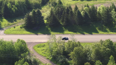 aerial, black luxury mclaren super car driving on rural countryside forest road