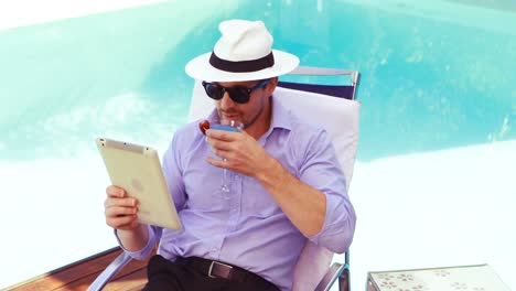 Handsome-man-using-tablet-and-drinking-cocktail