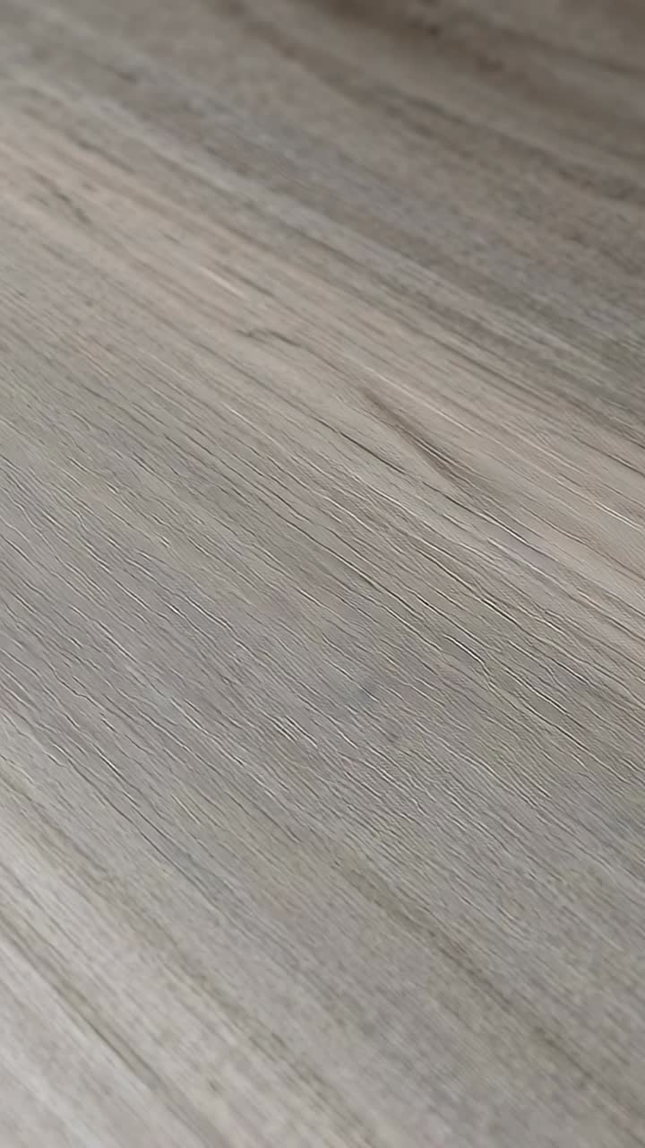 Vertical video: Starting playback, camera panning across gray wood panel indoors, showing grain