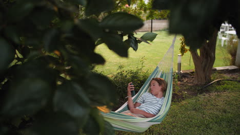 a young boy relaxes in a hammock in a backyard