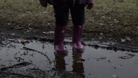 baby girl jumping with the waterproof pink boots on the puddle bambina salta con gli stivaletti rosa impermeabili nella pozzanghera