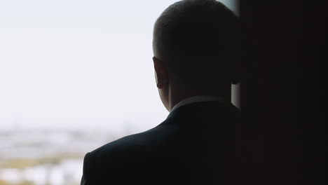 silhouette of businessman looking out of window in office