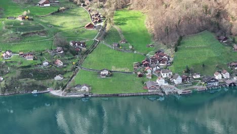 drone shot over lake walen in quinten in switzerland - lakeshore with houses and vineyards