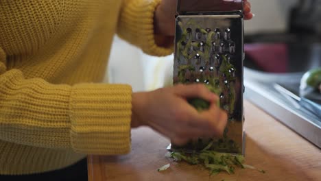 Closeup-of-a-woman-with-a-yellow-sweater-grating-some-cucumber-that-will-be-used-to-create-tzatziki