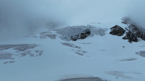 una vista impresionante de un glaciar que se mueve con gracia sobre un hombro rocoso, formando una delicada cascada de hielo en medio del paisaje nevado que lo abarca