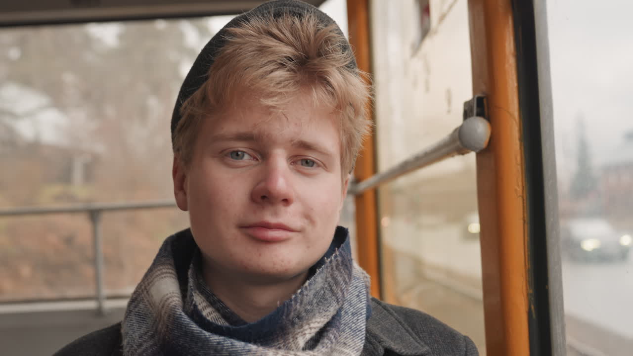 Smiling white creator filmmaker on tram, removing sunglasses with gentle smile, warm sunlight through window, suburban scenery passing, candid behind scenes energy and hopeful mood