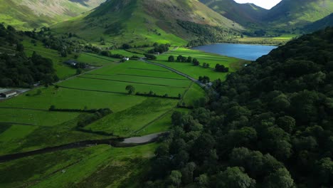 Forested-hillside-and-patchwork-green-fields-with-flight-towards-lake-Brothers-Water-and-mountains-of-Kirkstone-Pass