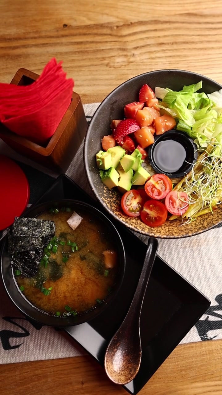 Poke bowl salutare e zuppa di miso serviti su un tavolo di legno