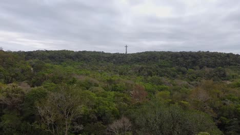 Drohnenaufnahme-Des-Argentinischen-Santa-Ana-Waldes-Mit-Kreuz-Im-Hintergrund,-Mittagsnachmittag-Mit-Blauem-Himmel-Und-Bewölkter-Landschaft-Rund-Um-Santa-Ana