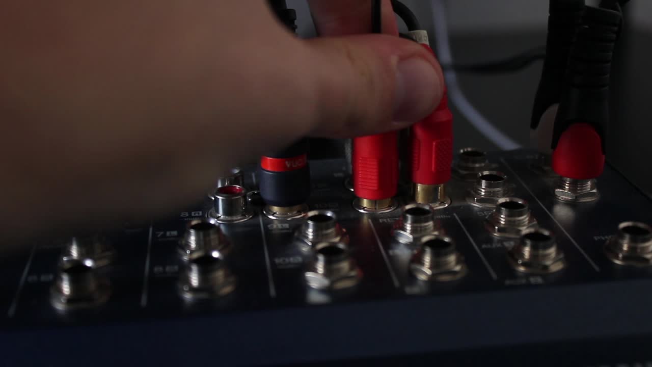 Hand Connecting Red Audio Cables to a Professional Mixing Console