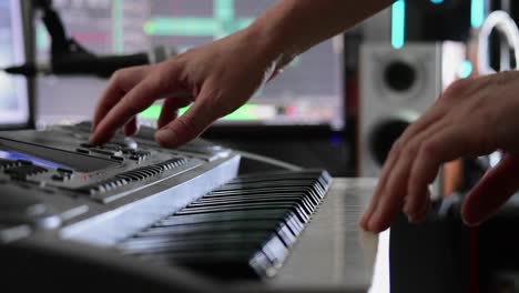 musician's hands select sounds on a keyboard in preparation for recording in a home studio