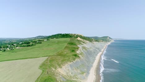 aerial panorama over a picturesque coastal location with cliffs sloping down towards a sandy beach