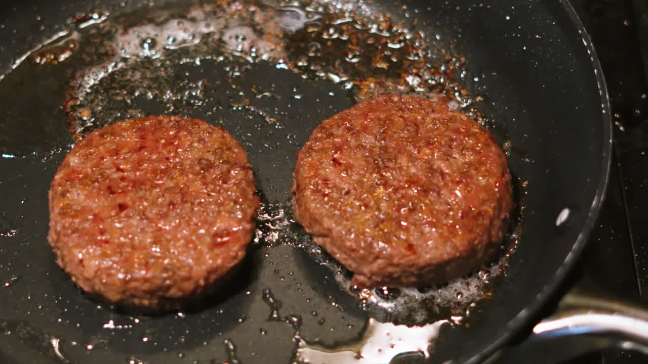 Overhead View of Beef Burgers Sizzling in Hot Frying Pan with Oil Bubbling with Fat 4K