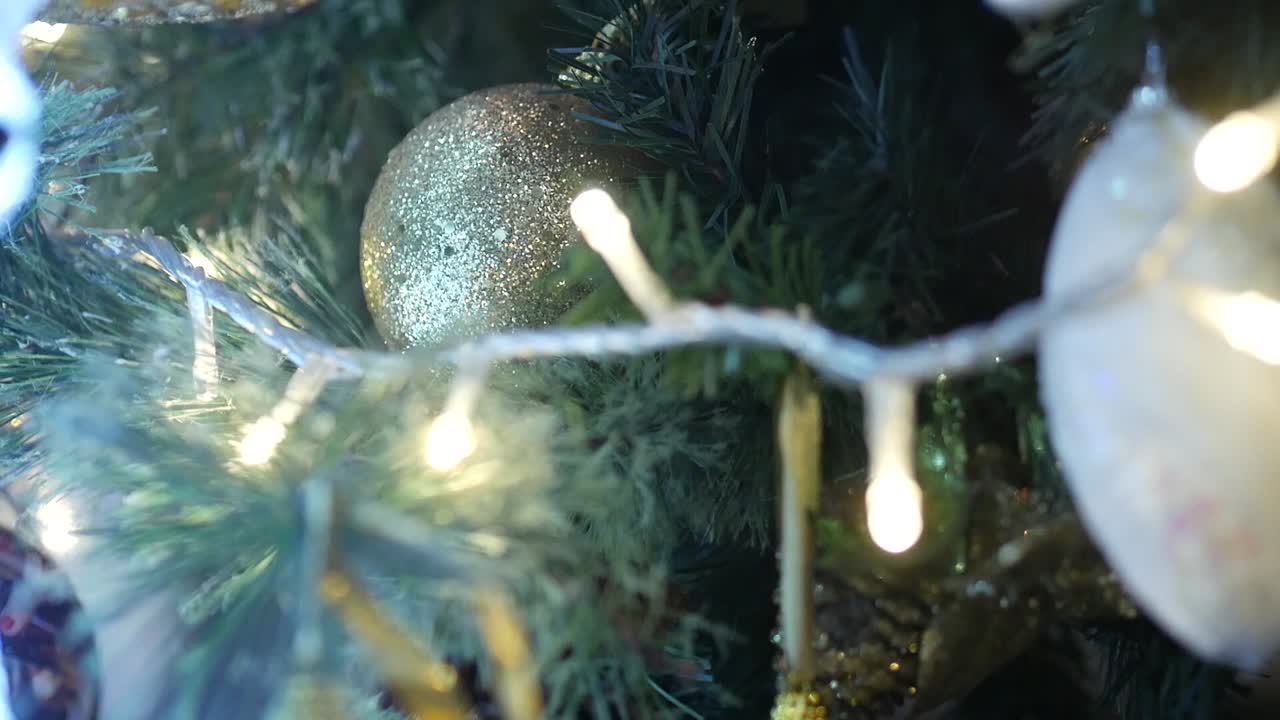 primer plano de adornos navideños en un árbol de navidad mientras las luces parpadean