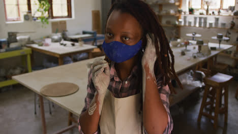 portrait of female african american potter with dirty hands in clay at pottery studio