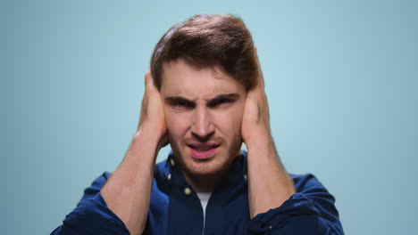 Man-holding-hands-on-head-at-blue-background.-Student-having-stress-in-studio