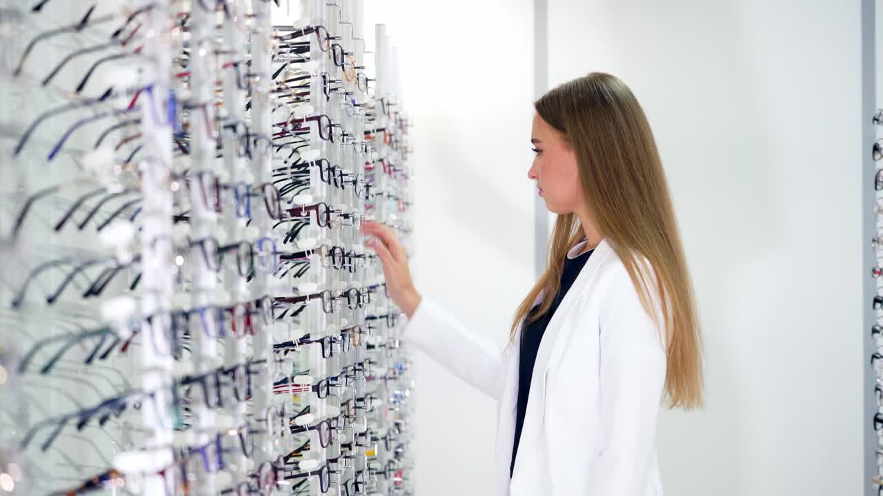 Optical store inside. Woman buyer choosing new eyeglasses. Beautiful woman trying on stylish spectacles. Vision concept.