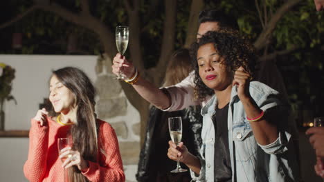 handheld shot of people with glasses of wine dancing at party