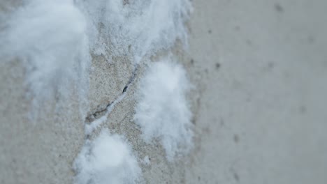 slowmotion closeup of snowballs hiting and splashing a concrete grey wall with crack