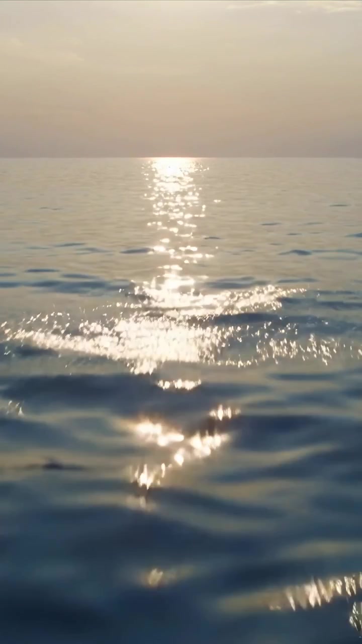 Vertical video: Glittering sun-glare band shifting at sea with small waves passing and craft moving