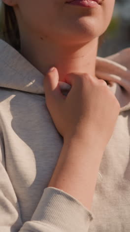 primer plano de la mano de la mujer sosteniendo suavemente la capucha, con la luz del sol proyectando un brillo cálido en su cara, el fondo está borroso, con un estadio vacío y árboles