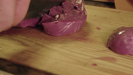 close-up: raw pig heart cut into strips on wooden chopping block