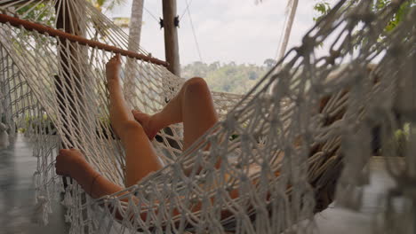 happy woman in hammock swaying peacefully on lazy summer day enjoying vacation lifestyle at holiday resort