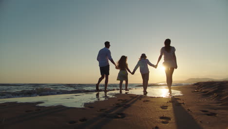 family walk on the beach at sunset