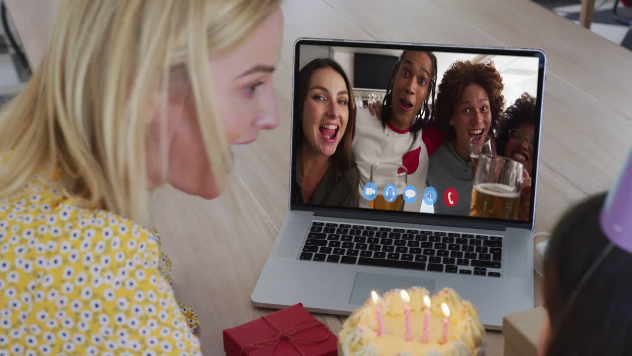Mãe e filha caucasianas sentadas à mesa usando laptop em videochamada de aniversário