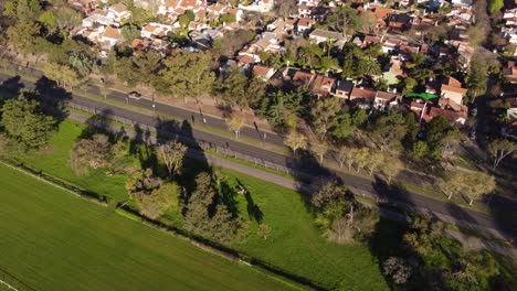 Aerial-view-of-a-pickup-truck-driving-by-avenue-in-green-area-Buenos-Aires,-Argentina