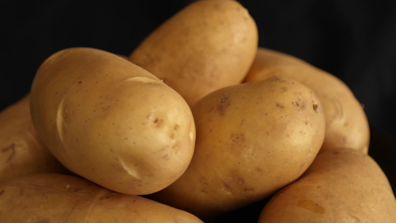patatas crudas que giran y giran aisladas sobre un fondo negro 3