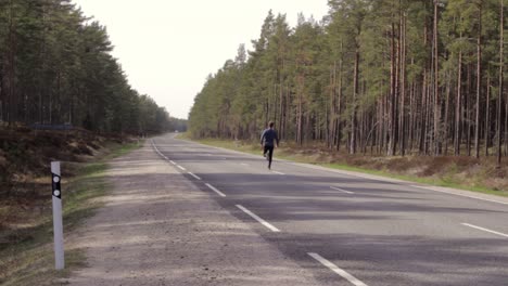 single marathon runner on middle of road, wears blue black clothes, static