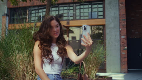 Asian-girl-photographing-herself-sitting-city-bench.-Girl-posing-on-phone-camera