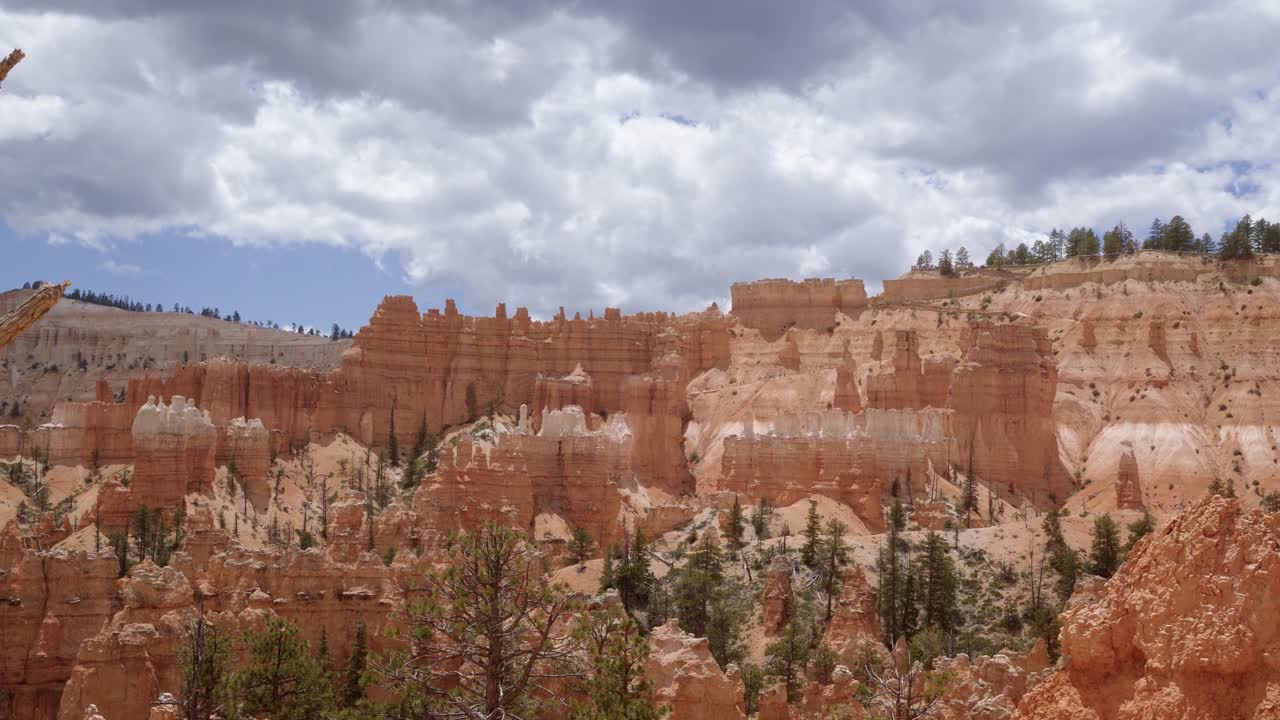 Tilt up shot of large orange sandstone hoodoo formations surrounded by greenery and trees in the desert of Southern Utah on a warm sunny summer day