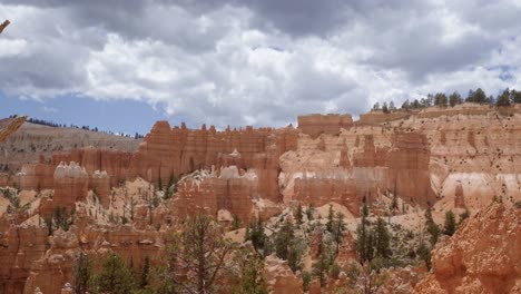 tilt up shot of large orange sandstone hoodoo formations surrounded by greenery and trees in the desert of southern utah on a warm sunny summer day