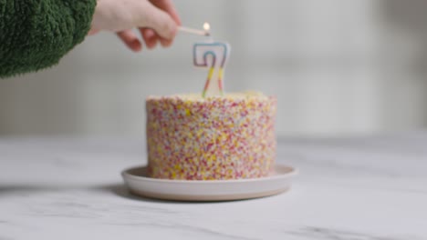 studio shot birthday cake covered with decorations and candle celebrating seventh birthday being lit