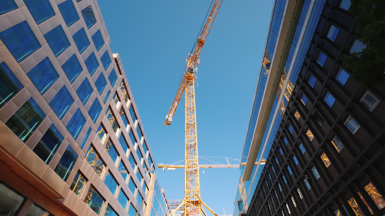 una gran grúa torre en el centro de los modernos edificios de oficinas de vidrio de la ciudad alrededor de la toma de steadicam