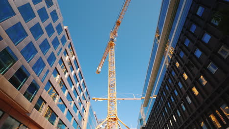 a large tower crane in the downtown of the modern city glass office buildings around steadicam shot