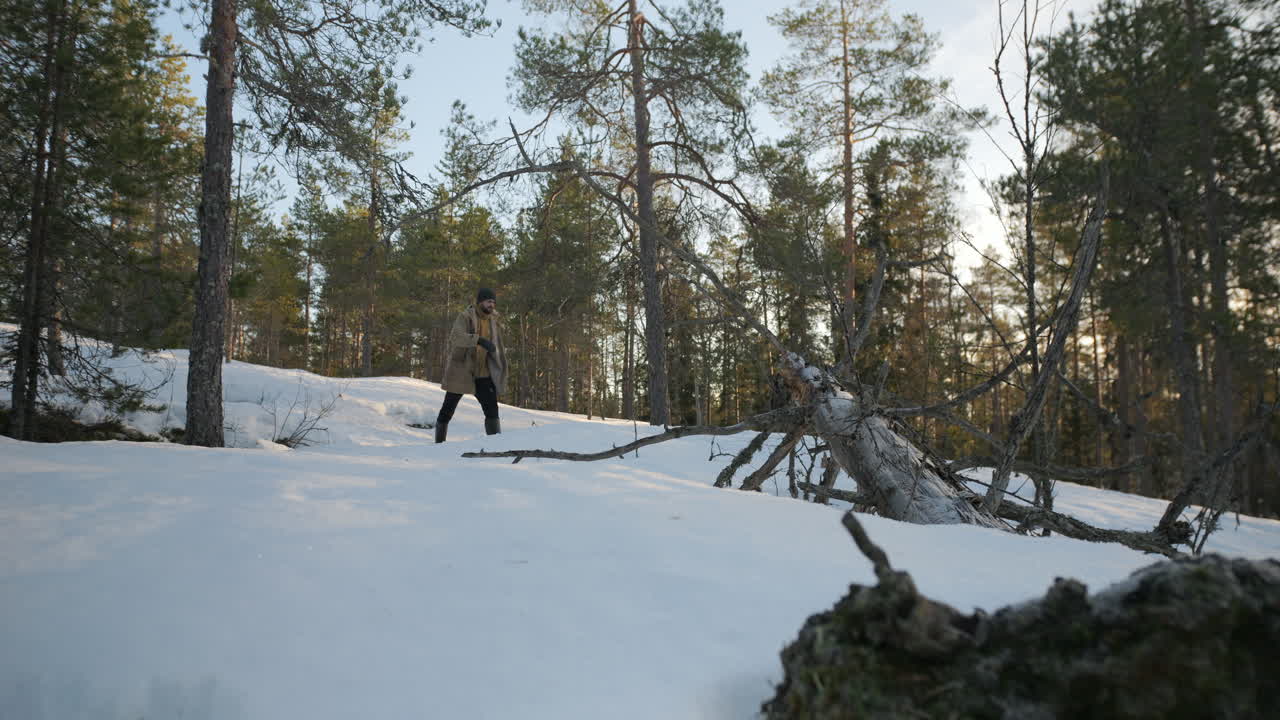 joven barbudo caminando en el bosque de invierno en un día frío, vista estática