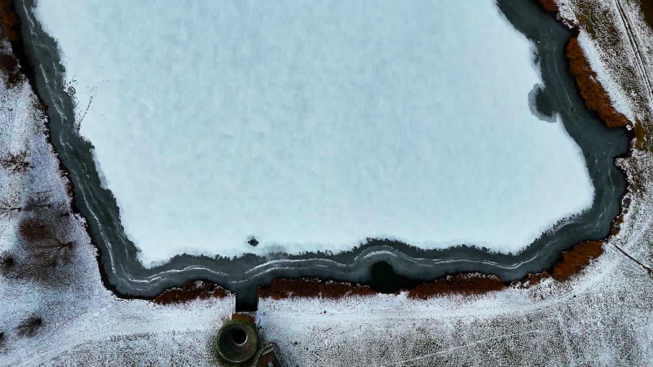 Aerial top-down descent over partially frozen lake with ice patterns, Czechia