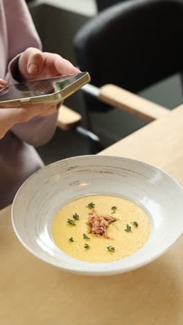 woman taking a photo of creamy soup